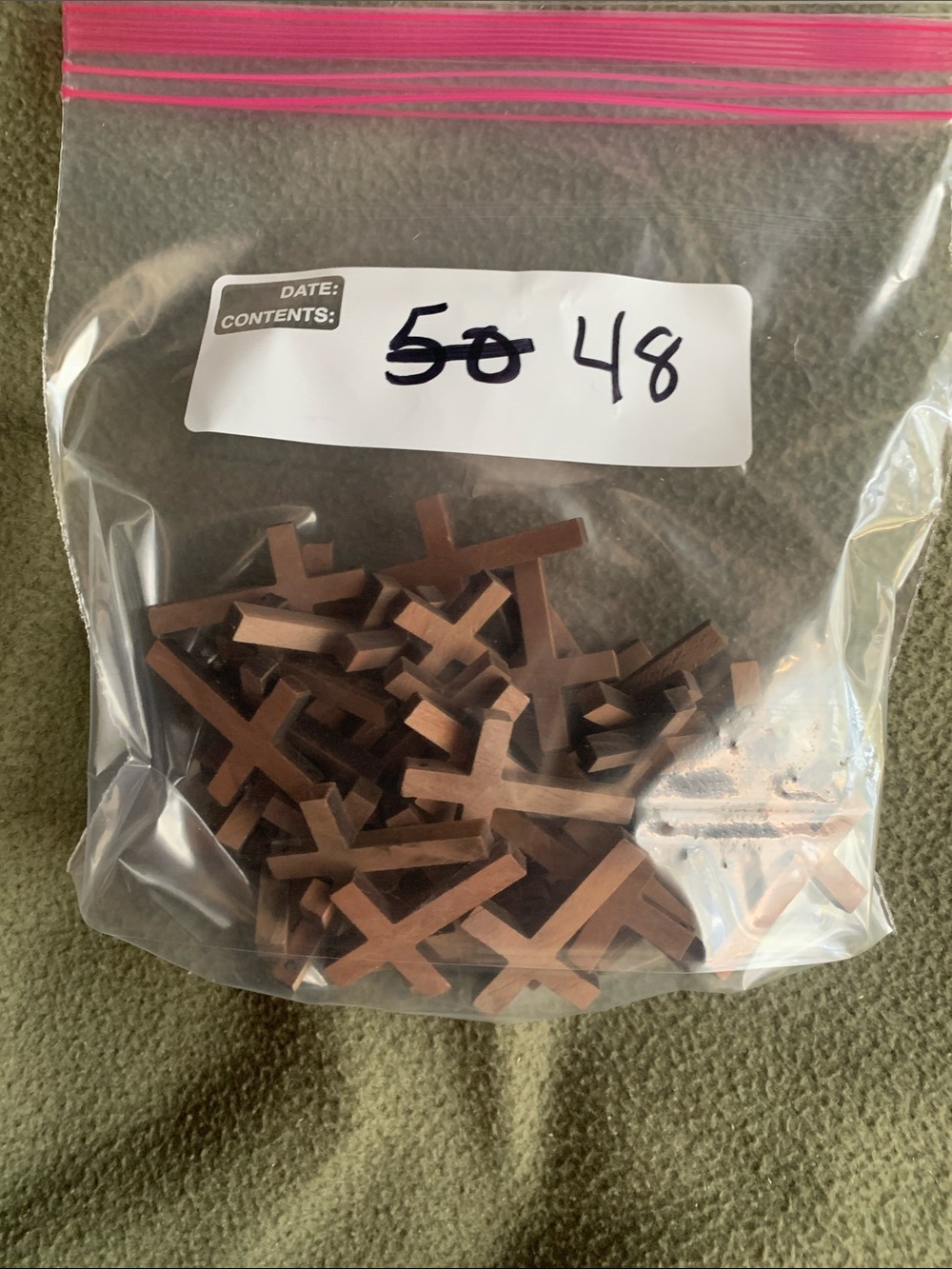 48 brown wooden crosses with holes. Approximately 1.2” x 1.75”
